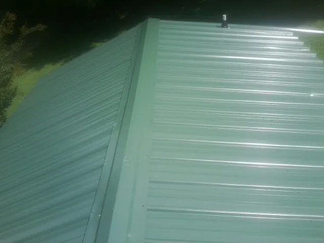 New green metal panels meeting at the ridge of a roof — Flat Roof Repair work by our crew in Bee