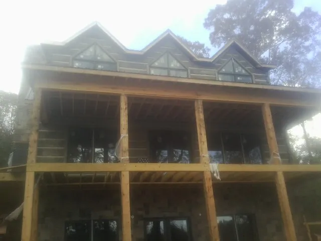 Dormers and porch framing on a large log home under construction — Roof Coating work by our crew in Bee