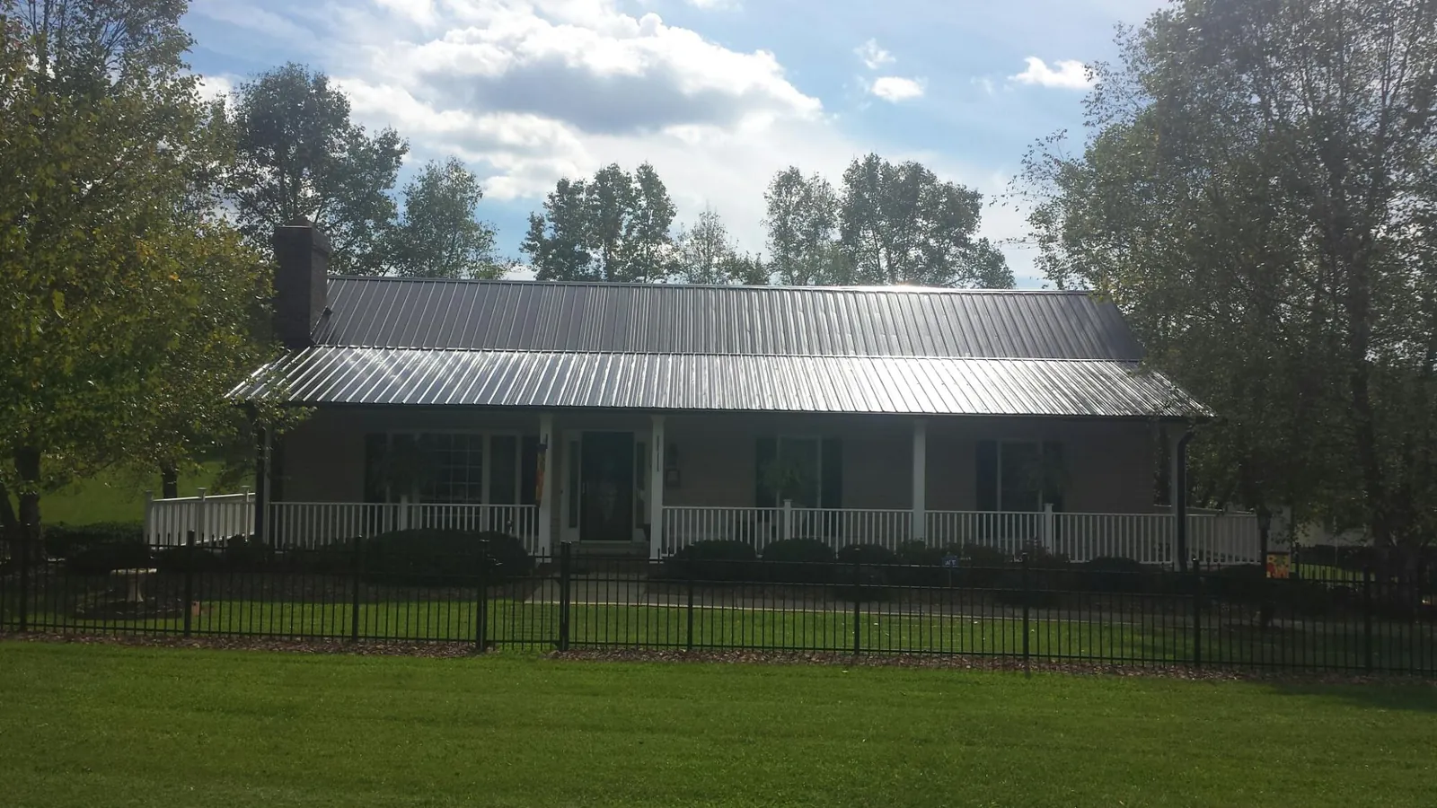 Gray metal roof on a brick ranch with a full width front porch — Gutter Guard Installation work by our crew in Bee