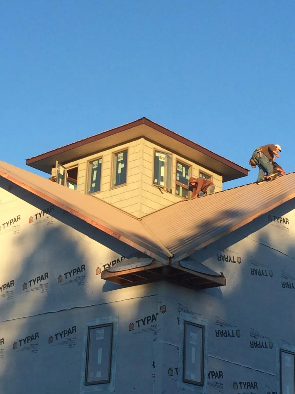 Roofers working around a rooftop cupola on a new metal roof at sunset — Roof Waterproofing in Bee by Roofing Brothers